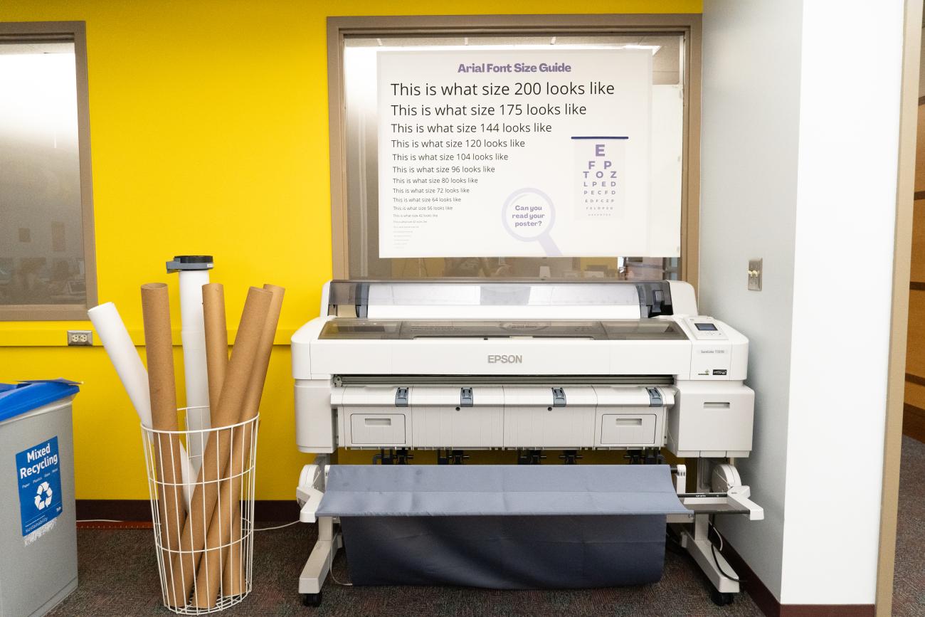 Large format printer and poster tubes in front of yellow wall