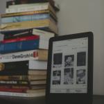 Ebook reader next to stack of books