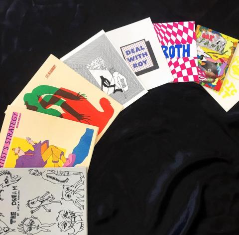 8 zines arranged in a semi circle, covers face up