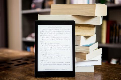 e-reader in front of stack of print books