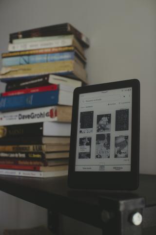 Ebook reader next to stack of books