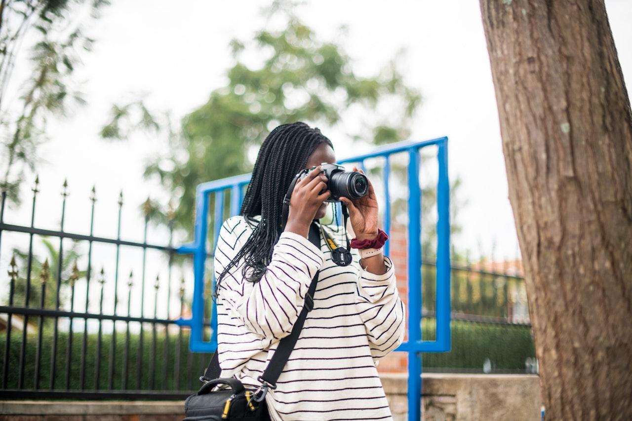 Black woman with long hair taking a photo outside