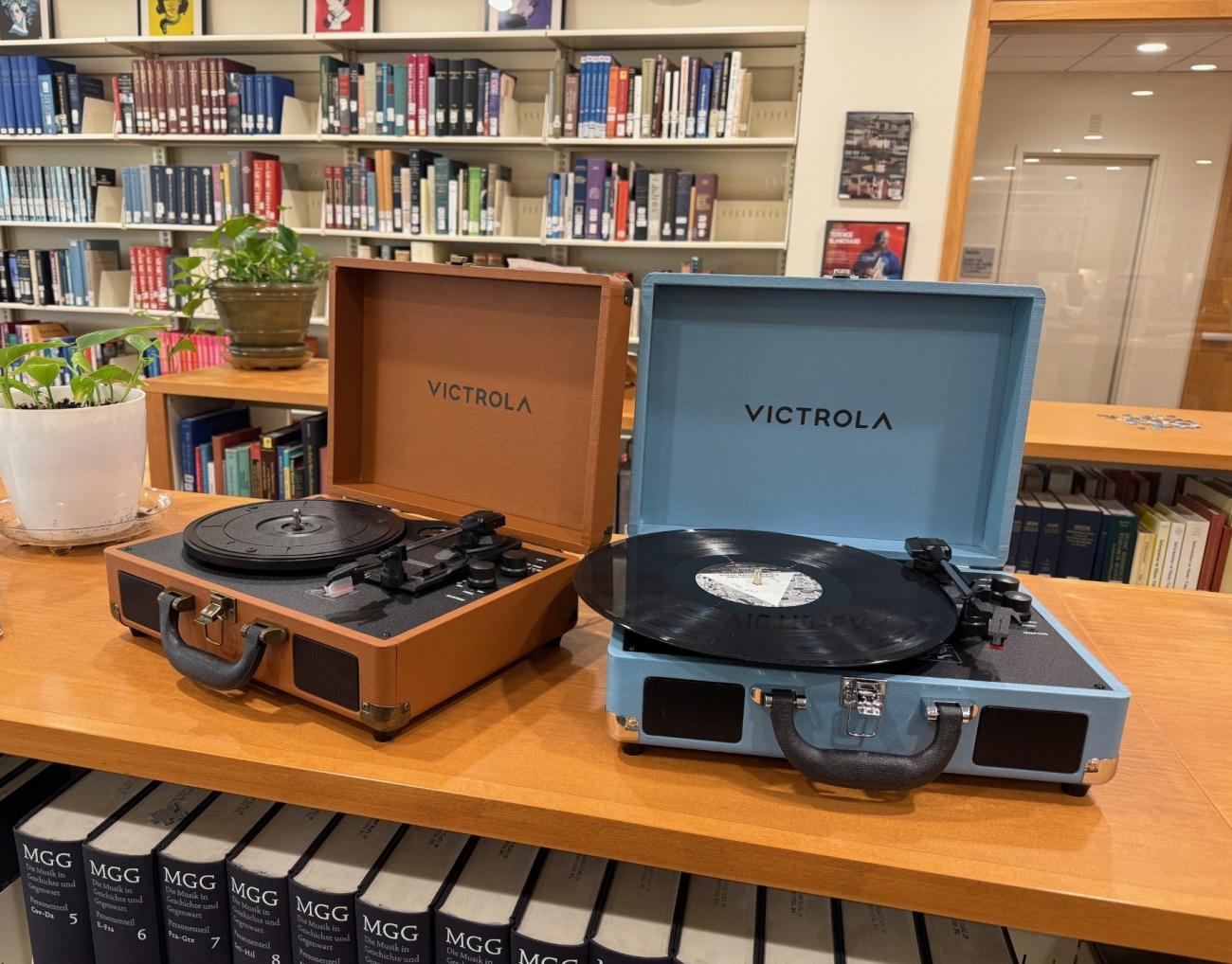One brown and one blue record player, open on the top of a shelf in the music library.