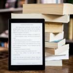 e-reader in front of stack of print books