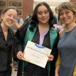 Three people pose for portrait, person in the center shows certificate